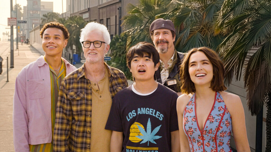 In a scene from Gail Daughtry and the Celebrity Sex Pass, Zoey Deutch, John Slattery, Ken Marino, Miles Gutierrez-Riley, and Ben Wang stand on a sidewalk and look at something off camera.