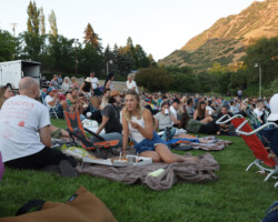 Moviegoers enjoying food and conversation before the Local Lens screening of 'Cha Cha Real Smooth.' Photographer: Ash Gerlach A seated woman eats a slice of pizza while conversing with someone