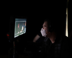 Lab fellow Hasan Hadi reviews footage for 'The President's Cake' during the 2022 Directors Lab. Photographer: Ash Gerlach Hasan Hadi's face is illuminated by the light of a viewing monitor in a dark space