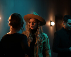 On the set of 'BLACK HOLE' with fellow Eliza McNitt during the 2022 Directors Lab. Photographer: Ash Gerlach A woman in a hat talks, illuminated by bluish green and orange light