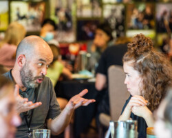 Creative advisor Adriano Goldman (left) and lab fellow Caledonia Curry converse during lunch. Photographer: Jonathan Hickerson Adriano talks with his hands gesturing upwards as Caledonia listens