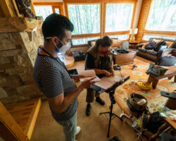 Lab fellow Michael León (left) and script supervisor Donna Parish (right) review lines for 'Crabs in a Barrel.' Photographer: Sam Emenogu Michael and Donna stand in an lodge living room