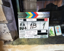 The slate for Michael León's project, 'Crabs in a Barrel' during the 2022 Directors Lab. Photographer: Sam Emenogu A slate on stone window ledge alongside two vintage religious paper cards