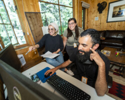 Lab fellow Jude Chehab, contributing editor Stephanie Andreou (middle), and editor and producer Fahd Ahmed (right) work on 'Q.' Photographer: Miguel Mendoza Fahd, Stephanie, and June gather around an editing screen