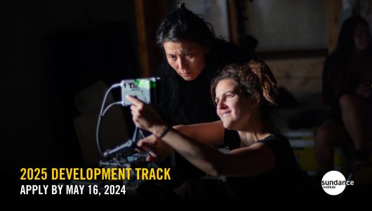 Two women crouch before film camera monitor watching the video playback. Text over image reads: 2025 Development Track. Apply by May 16, 2024. Sundance Institute logo appears in bottom right corner.