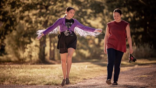 Two young indigenous women are walking on a street